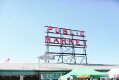 a sign that says public market on top of a building with people walking around it