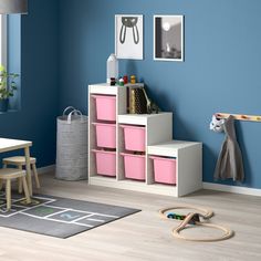 a child's room with blue walls and pink storage bins on the floor