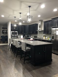 a large kitchen with black cabinets and an island in front of the stove top oven