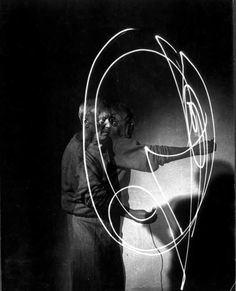 a man holding a light painting in front of a black and white photo with the letter q on it