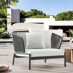 an outdoor lounge chair with two pillows on it and some tables in front of the pool