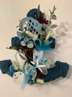 an arrangement of flowers and feathers on a white surface with blue ribbon around the stems