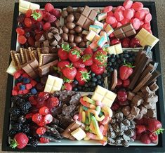 a tray filled with lots of different types of fruit and chocolates on top of each other