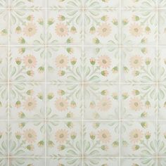 a white tiled wall with pink and green flowers painted on the tiles in different colors