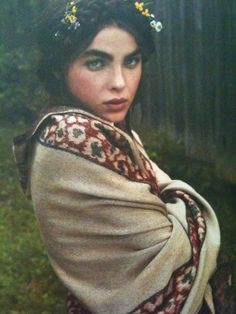 a woman wearing a shawl with flowers in her hair is posing for the camera