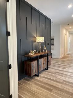 a room with wood flooring and black walls, two lamps on top of the table