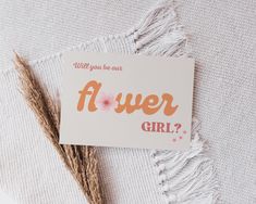 a sticker that says, will you be one flower girl? on it next to some dried grass