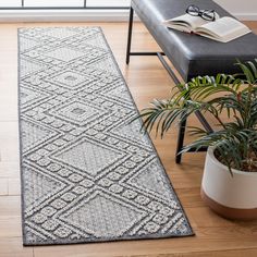 a large rug in the middle of a living room next to a chair and potted plant