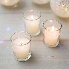 three candles sitting on top of a table next to other small glass vases filled with water