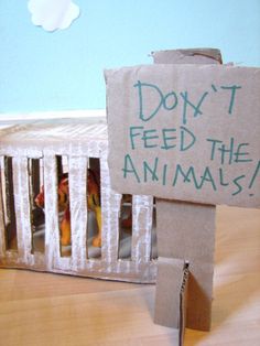 a cardboard sign that says don't feed the animals in front of a cage