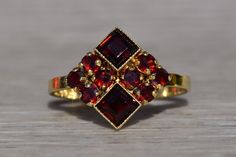 The Amwell: Ladies Signed 14K Mid Century Cocktail Ring set with Garnet. Crafted in 14 karat yellow gold is this vintage mid century styled ring set throughout with garnets. From North to South, you will see two square emerald cut garnets bezel set and decorated with fine milgrain. To the left and right are four round cut diamonds on either side. Currently the ring is a finger size 6.5 and is able to be resized for an additional fee upon request. Formal Yellow Gold Garnet Cluster Ring, Vintage Ruby Cluster Ring For Formal Occasions, Vintage Ruby Cluster Ring For Formal Events, Vintage Multi-stone Ruby Ring In 14k Gold, Vintage Multi-stone Ruby Cluster Ring, Vintage 14k Gold Multi-stone Ruby Ring, Vintage Multi-stone Garnet Jewelry, Vintage Style Red Cluster Ring In 14k Gold, Vintage Ruby Multi-stone Cluster Ring