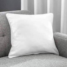 a white pillow sitting on top of a gray couch