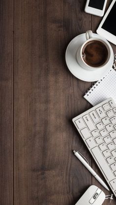 a wooden table topped with electronics and a cup of coffee