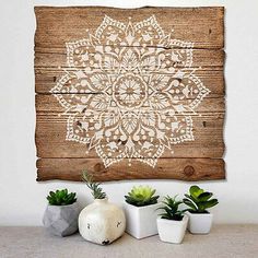 some succulents are sitting on a table next to a wooden wall hanging