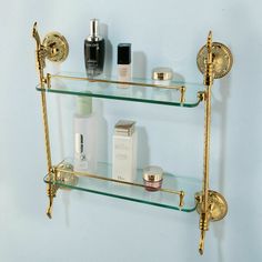 two glass shelves with gold fixtures and perfumes on the top, one shelf is filled with personal care items