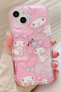 a person holding a pink phone case with hello kitty on it