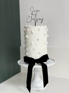 a white cake with black ribbon and name on it