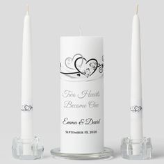 two white candles sitting next to each other on top of a glass stand with the words love heals become one