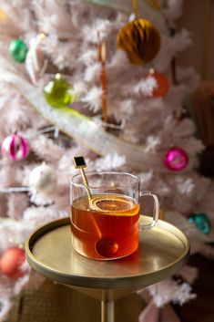 a cup of tea sitting on top of a table next to a christmas tree