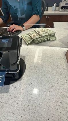 a woman sitting at a cash register with money in front of her laptop and on the counter