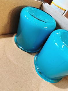 two blue vases sitting on top of a cardboard box