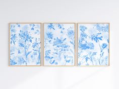 three blue and white paintings hanging on the wall