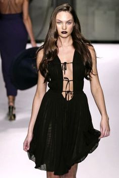 a model walks down the runway in a black dress with cutouts on her back