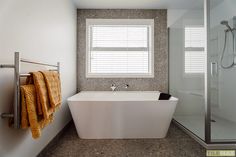 a white bath tub sitting under a window next to a shower