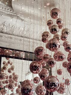 a chandelier with lots of shiny balls hanging from it's ceiling in front of a mirror