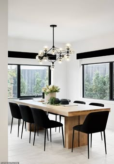 a dining room table with black chairs and a chandelier