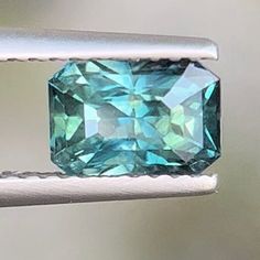 a blue green diamond sitting on top of a white piece of metal next to a window