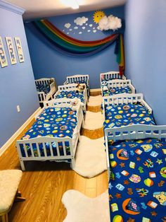 there are many beds in this room with the rainbow painted on the wall behind them