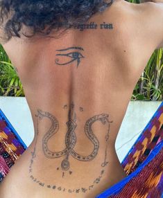 the back of a woman's body with an egyptian symbol tattooed on her lower back