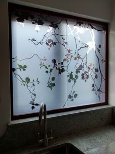 a kitchen sink under a window with leaves on it