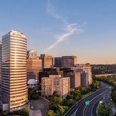 an aerial view of a city with tall buildings and trees in the foreground at sunset