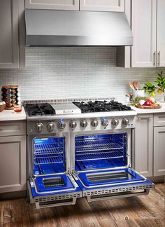 two open ovens in a kitchen with white cabinets and wood flooring on the side