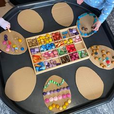 two children are playing with their crafts on the tray in the shape of an egg