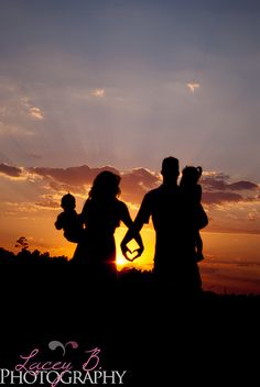 the silhouettes of two people holding hands as the sun sets in the sky behind them