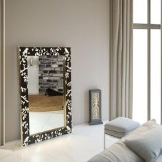 a large mirror sitting on top of a white table next to a couch and window