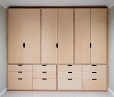 an empty room with several wooden drawers and cupboards in the corner, all lined up against the wall