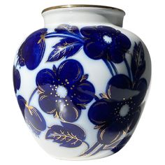 a blue and white vase with flowers painted on the outside, gold trimmings