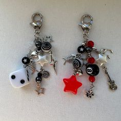 two key chains with charms attached to them on a white tablecloth covered surface, one has a red star and the other is a black and white dice