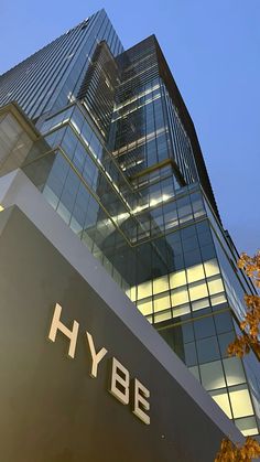 the hybe building is very tall and has many windows on each side,