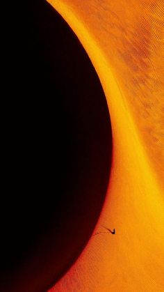 the shadow of a person on a surfboard is seen in front of an orange sand dune