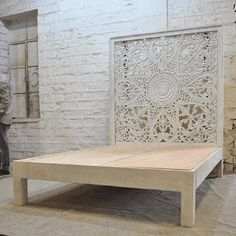 a white bed frame sitting on top of a wooden floor next to a brick wall