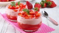 two small bowls filled with strawberries on top of a table