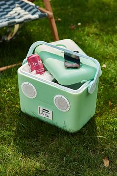 an ice chest is sitting in the grass with a cell phone on top of it