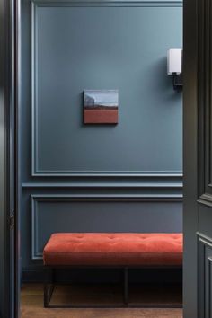 an orange bench in front of a blue wall