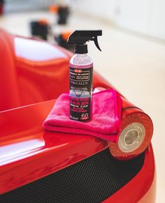 a red car with a pink cloth on it and a spray bottle next to it