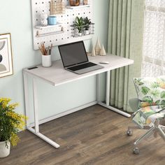 a laptop computer sitting on top of a white desk next to a chair and potted plant